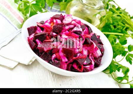 Salade Vinaigrette au vinaigre ou avec de la choucroute, pommes de terre, betterave et oignon, assaisonné d'huile végétale dans un bol, serviette, le persil sur l'arrière-plan de Banque D'Images