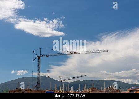 Une grue mobile avec des équipements accrochés à une extrémité se déplace sur un chantier de construction avec la montagne de Monte Serra en arrière-plan, Bientina, Pise, Italie Banque D'Images