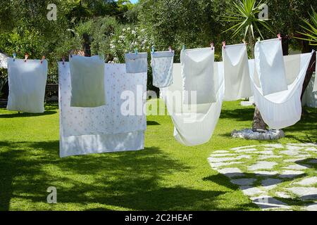 Blanchisserie de draps et oreillers sécher par temps ensoleillé dans un jardin avec l'herbe verte d'une villa d'été. Banque D'Images