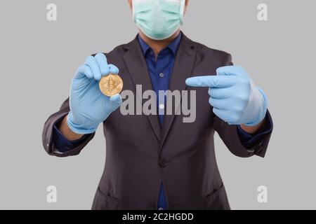 Homme d'affaires pointant sur Bitcoin portant un masque médical et des gants. Devise Cypto homme d'affaires. Banque D'Images