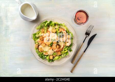 Salade de crevettes au parmesan, croûtons et laitue, avec un verre de vin rose et une sauce voile Banque D'Images