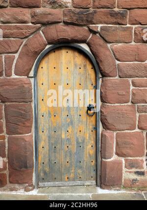 une ancienne porte en bois marron dans un mur médiéval en grès rouge Banque D'Images