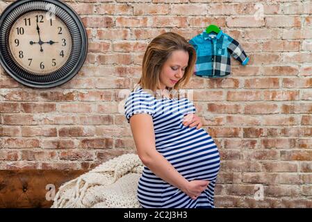 Belle femme enceinte assis près de brick wall Banque D'Images