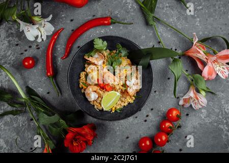 Riz thaïlandais avec crevettes dans une assiette noire sur fond sombre. copyright place Banque D'Images