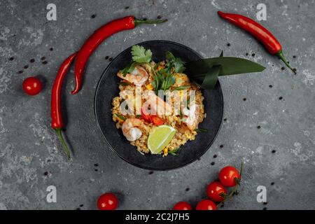 Riz thaïlandais avec crevettes dans une assiette noire sur fond sombre. copyright place Banque D'Images