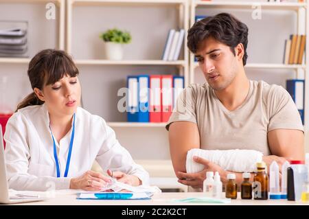 Jeune homme au bras bandé visiter médecin femme traumatologist Banque D'Images