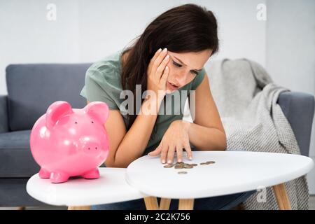 Jeune femme malheureuse de vider sa tirelire épargne avec moins que prévu à la maison Banque D'Images