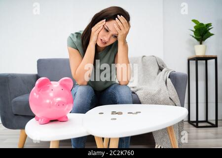 Jeune femme malheureuse de vider sa tirelire épargne avec moins que prévu à la maison Banque D'Images