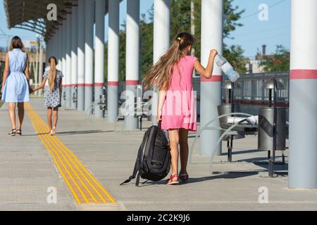 La fille et la fille sont marcher le long de la plate-forme de la gare, une autre fille avec un grand sac à dos est d'essayer de rattraper avec eux Banque D'Images