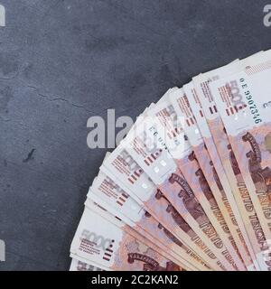 Pile de billets de l'argent russe de cinq mille roubles couché ventilateur sur une base de ciment gris Banque D'Images