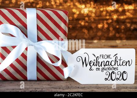Un cadeau de Noël avec étiquette avec calligraphie allemand Frohe Weihnachten und ein 2020 Glueckliches veut dire Joyeux Noël et une Bonne 2020. Pap d'enrubannage Banque D'Images