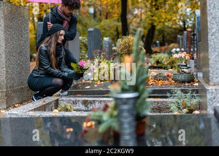 Couple dans la douleur sur un cimetière en automne alors qu'il pleut Banque D'Images