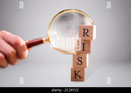 Entrepreneur's Hand Holding loupe sur la pile de blocs en bois mot risque Banque D'Images