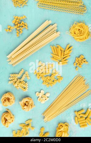 Mise à plat de pâtes italiennes, de l'affiche en plongée des sur un fond bleu. Spaghetti, penne, farfalle et autres types, vue du dessus Banque D'Images