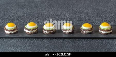 Canape avec fromage à la crème, guacamole et oeufs de caille frit sur la plaque Banque D'Images