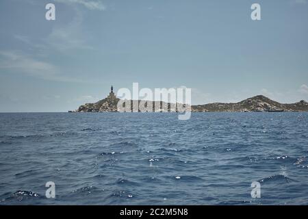 Marin avec un phare au loin vu de la mer sous un ciel d'été. Banque D'Images