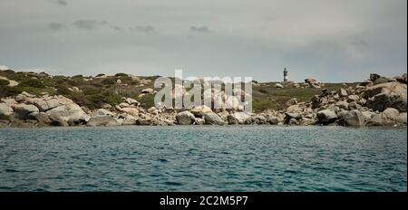 Leuchtturm niché dans un promontoire naturel mis au point à l'horizontale sous le liea et ciel nuageux pris dans au milieu de la mer. Banque D'Images