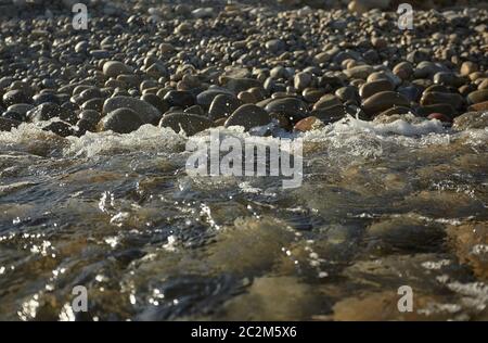 L'eau cristalline de la mer du sud de la Sardaigne se réunit avec la plage rocheuse se brisant sur les pierres. Banque D'Images