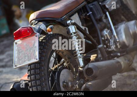 Arrière d'une moto d'époque avec le feu rouge au milieu et d'autres pièces mécaniques sur l'affichage. Banque D'Images