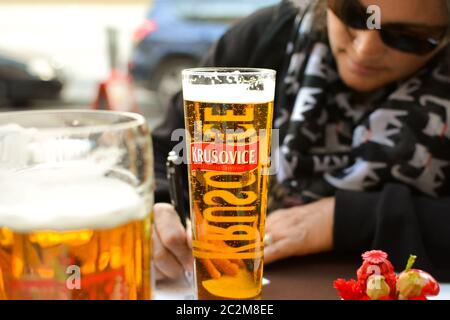 Une femme portant des verres sombres et buvant une bière remplit des cartes postales dans un café-terrasse de Budapest Hongrie. Banque D'Images