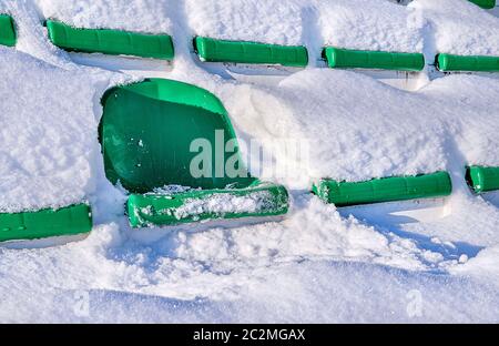 Les sièges verts d'un stade sportif, couverts de neige. Le concept de la fermeture de la saison estivale des jeux. Banque D'Images