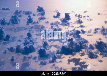 Belle vue depuis la fenêtre de l'avion volant sur les nuages et la surface de la mer Banque D'Images