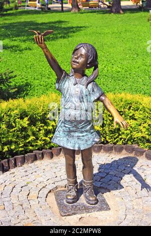 Sculpture en bronze de petite fille levant la main dans le parc de la ville. Monument à la petite fille Banque D'Images