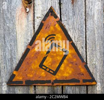 Icône de smartphone sur le panneau d'avertissement jaune triangulaire météo. Fond Grange. Banque D'Images