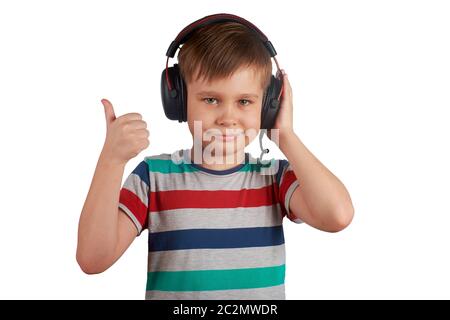 Kid écoute sa musique préférée sur son casque et montre le pouce vers le haut , isolé sur fond blanc. Concept de loisirs, musique et divertissement Banque D'Images