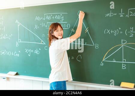 étudiant en classe en écriture sur des équations mathématiques de tableau de surveillance Banque D'Images