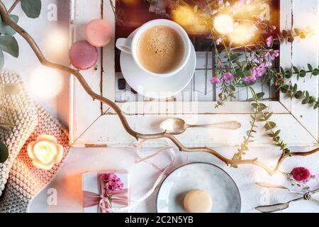 Décoration de fête des mères dans un style vintage lumineux avec des macarons colorés et une tasse de café. Fleurs encore la vie avec le bokeh atmosphérique pour un petit déjeuner ba Banque D'Images
