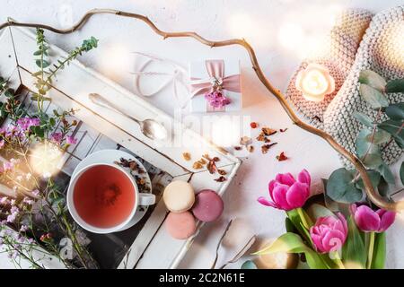 Décoration de fête des mères dans un style vintage lumineux avec des macarons colorés et une tasse de thé. Fleurs encore la vie avec le bokeh atmosphérique pour un petit déjeuner Banque D'Images