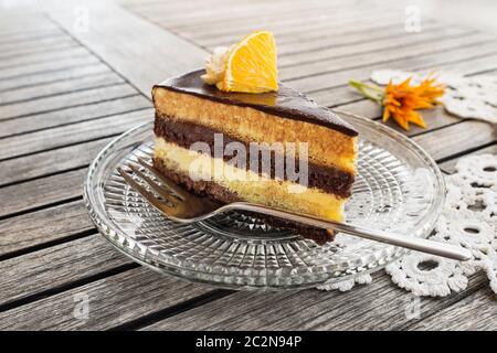 Tranche de gâteau au chocolat savoureux avec crème aux fruits sur fond de table en bois, closeup. Gâteau au chocolat. Banque D'Images