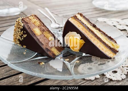 Gâteau au chocolat tranché avec crème et noix sur fond de table en bois, closeup. Morceaux de gâteau au chocolat. Banque D'Images