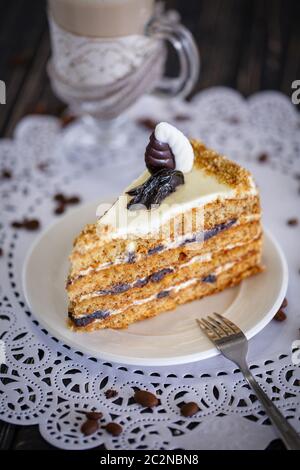 Gâteau au miel et pruneaux sur une assiette blanche. Gâteau sur la table dans le café. Banque D'Images