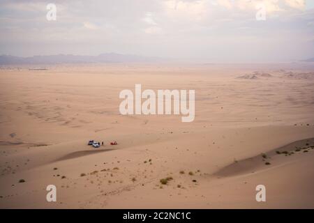 Image aérienne stupéfiante d'un désert de dunes de sable avec deux SUV et deux peronas campant dans des tentes dans le désert près de Badr, Arabie Saoudite Banque D'Images