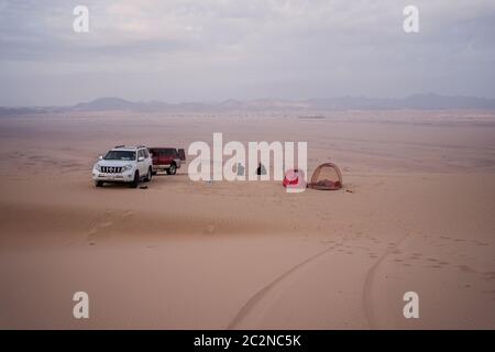 Désert de Badr / Arabie Saoudite - 20 janvier 2020 : superbe image aérienne du désert de dunes de sable avec deux SUV et deux camping de peronas dans des tentes dans le désert près de Badr Banque D'Images