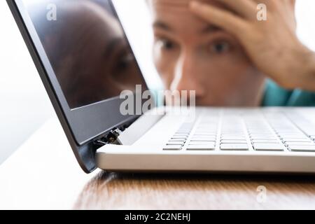 Man Looking At endommagé Ordinateur portable avec écran cassé Pièce jointe Banque D'Images