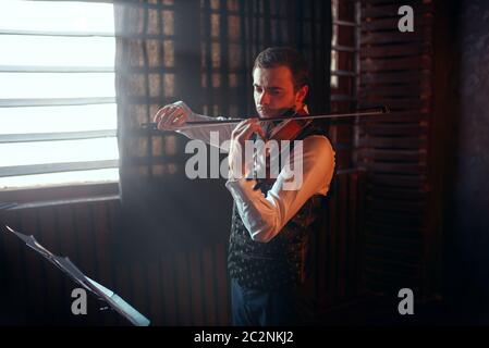 Violoniste mâle jouant au violon contre la fenêtre. Fiddler homme avec instrument de musique Banque D'Images