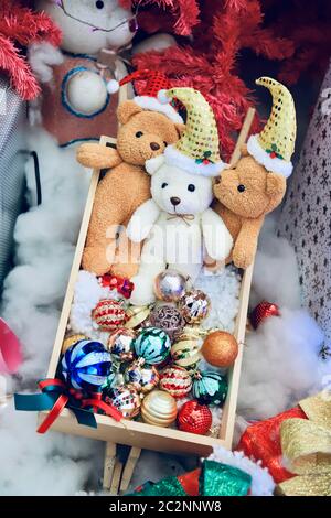 De nombreux ours en peluche sont dans une boîte en bois remplie de décorations de Noël. Le sol est recouvert de coton blanc. Sélectionnez la mise au point. Banque D'Images