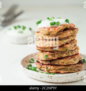 Beignets de courgettes. Beignets de courgettes traditionnelles en pile sur fond blanc. Crêpes ou beignets de courgettes avec oignon vert et parmesan, service Banque D'Images