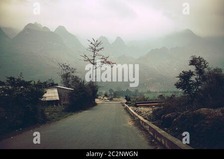 Paysage cinématographique sombre et sinistre de la route de montagne couverte de brouillard à Meo vac, province de Ha giang au nord du Vietnam Banque D'Images