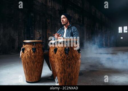 Le batteur joue sur l'homme dans des fûts en bois magasin d'usine, musicien en mouvement. Bongo, musical instrument à percussion, musique ethnique Banque D'Images