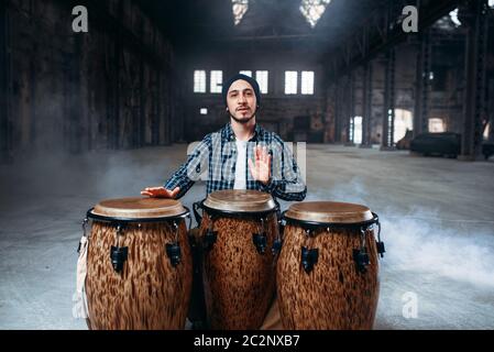 Le batteur joue sur l'homme dans des fûts en bois magasin d'usine, musicien en mouvement. Bongo, musical instrument à percussion, musique ethnique Banque D'Images