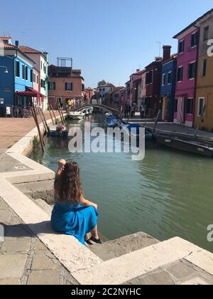 Fille assise sur un canal à Burano Banque D'Images