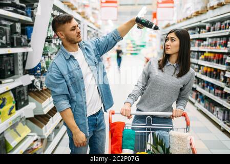 Couple avec le chariot de marché, des outils électriques, ministère family shopping. Les clients en boutique, le choix des acheteurs de biens de consommation Banque D'Images