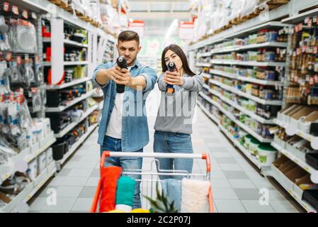 Couple avec tournevis électrique, outils électriques ministère en supermarché, faire du shopping. Les clients en boutique, le choix des acheteurs de biens de consommation Banque D'Images