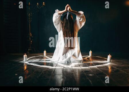 Femme avec couteau en mains assis en cercle avec pentagramme bougies. Rituel de magie noire, l'occultisme et d'exorcisme, un pouvoir surnaturel Banque D'Images