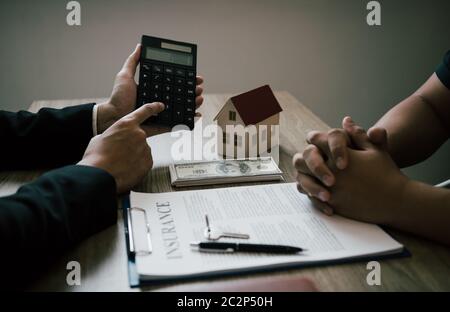 Les agents calculent le taux de paiement du prêt ou le montant des primes d'assurance pour les clients qui viennent contacter l'achat d'une nouvelle maison à l'extérieur Banque D'Images