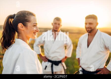 Deux hommes et une femme karatéka sur la formation en cours d'été à l'extérieur. Art Martial, technique de plein air d'entraînement pratique Banque D'Images